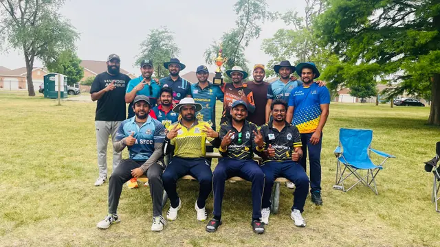 Cricketers posing together on grass with trees behind them.